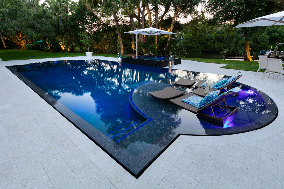 Foto de piscinas y jacuzzis alargados actuales de tamaño medio a medida en patio trasero con adoquines de hormigón
