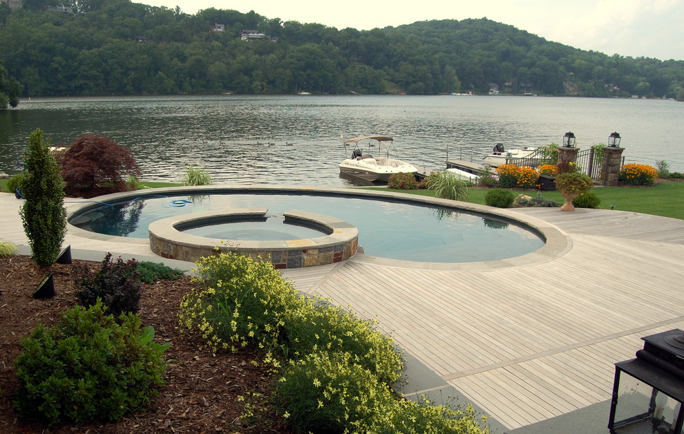 Foto di una piscina naturale a "C" di medie dimensioni e dietro casa con una vasca idromassaggio e pedane