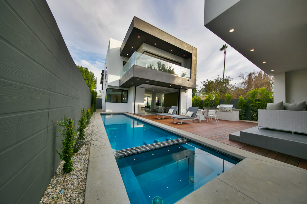 Immagine di una piscina monocorsia minimalista rettangolare dietro casa con lastre di cemento