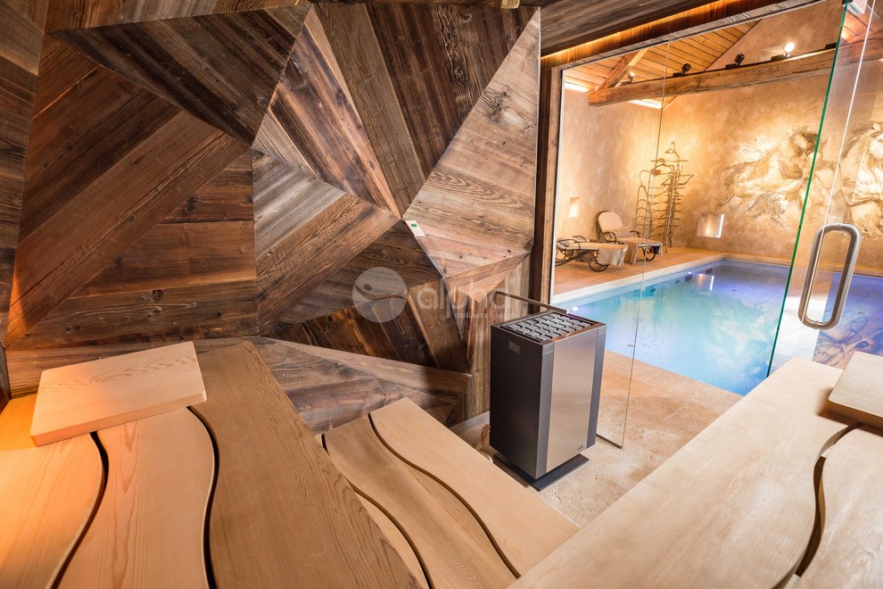 Idée de décoration pour une grande piscine chalet rectangle avec un bain bouillonnant et des pavés en pierre naturelle.