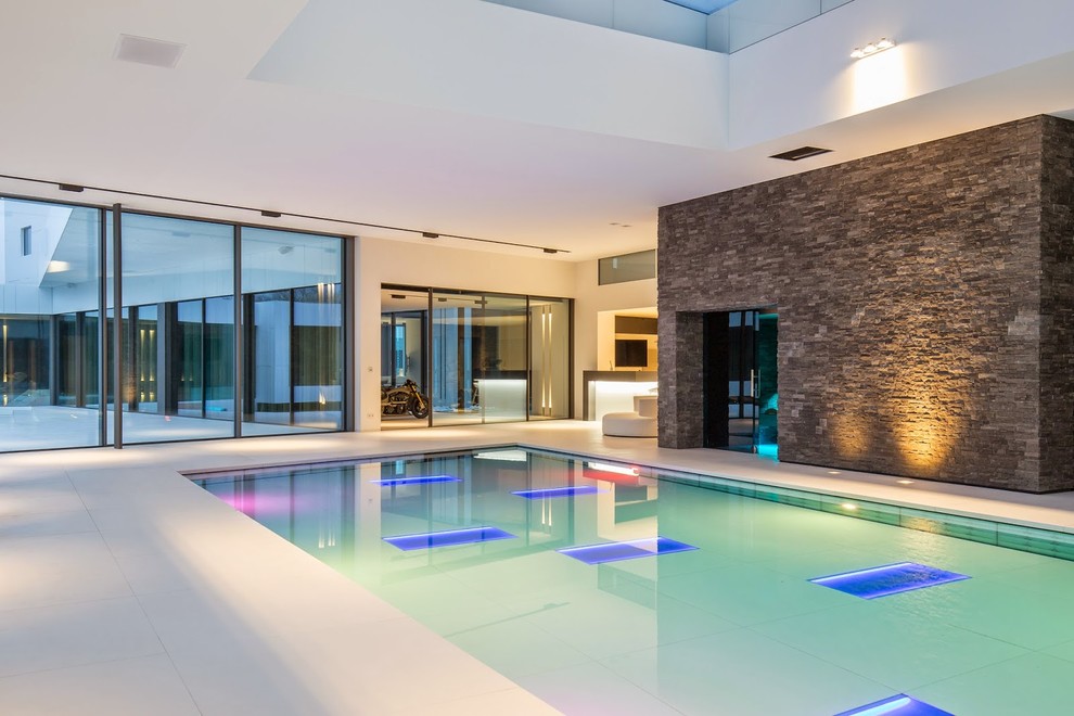 Ispirazione per un'ampia piscina coperta monocorsia minimal rettangolare con una vasca idromassaggio e pavimentazioni in pietra naturale