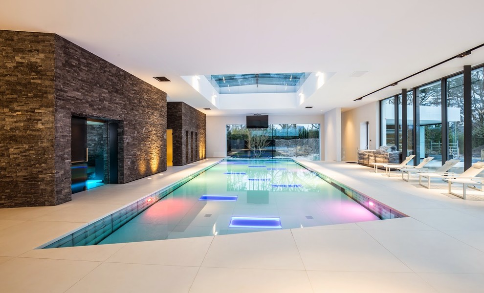 Esempio di un'ampia piscina coperta monocorsia design rettangolare con una vasca idromassaggio e pavimentazioni in pietra naturale