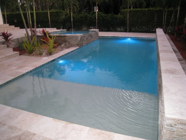 Traditional back rectangular hot tub in Miami with stamped concrete.