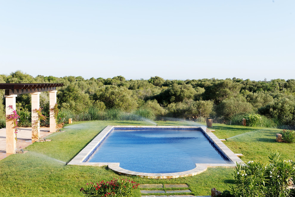Ejemplo de piscina alargada mediterránea grande a medida en patio trasero con losas de hormigón
