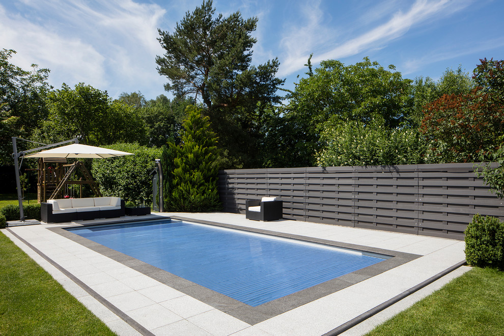 Diseño de piscina alargada minimalista de tamaño medio rectangular con adoquines de piedra natural