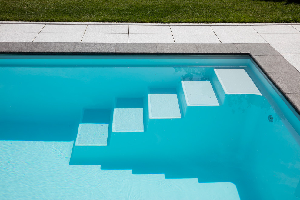 Aménagement d'un couloir de nage moderne de taille moyenne et rectangle avec des pavés en pierre naturelle.