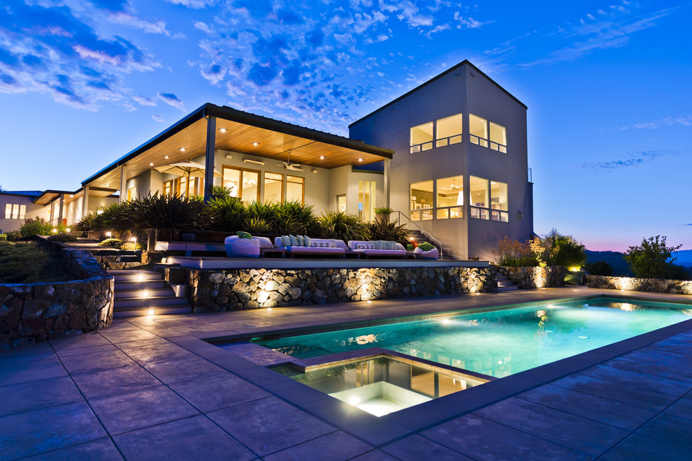 Imagen de piscinas y jacuzzis alargados contemporáneos extra grandes rectangulares en patio trasero con losas de hormigón