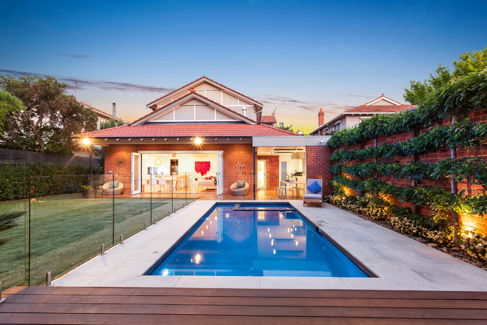 This is an example of a contemporary back rectangular swimming pool in Melbourne with decking.
