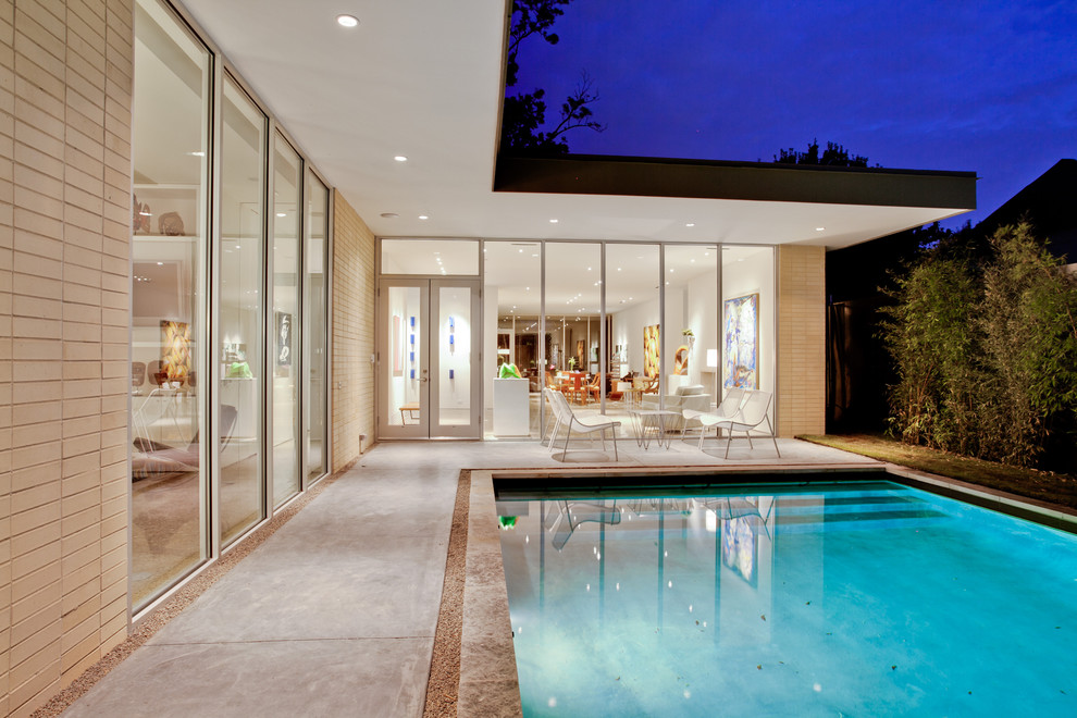 Пример оригинального дизайна: прямоугольный бассейн в стиле модернизм с покрытием из бетонных плит