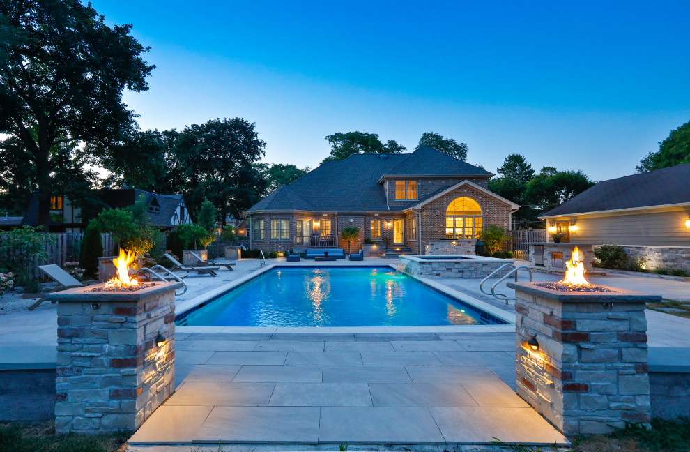 Ejemplo de piscina alargada tradicional de tamaño medio rectangular en patio trasero con paisajismo de piscina y adoquines de piedra natural