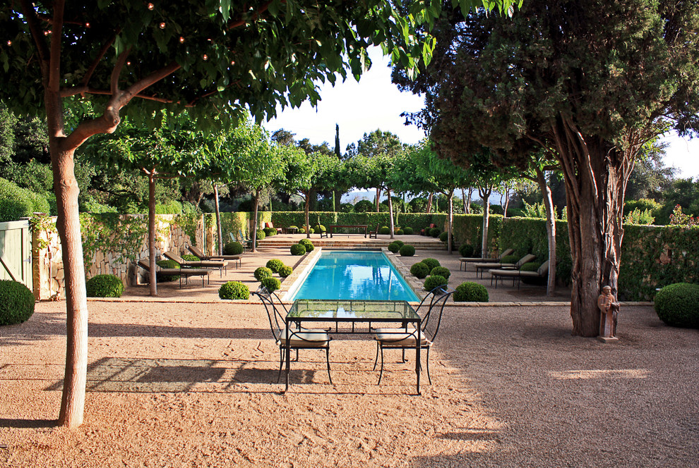 На фото: спортивный, прямоугольный бассейн на внутреннем дворе в средиземноморском стиле с покрытием из гранитной крошки и забором