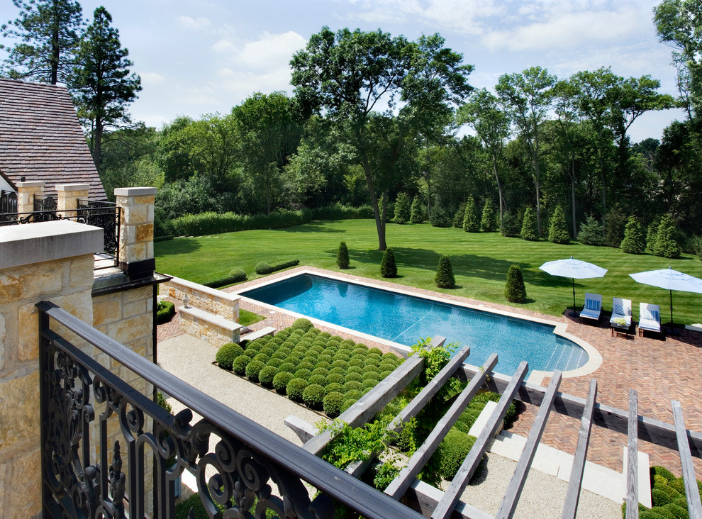 На фото: огромный прямоугольный бассейн на заднем дворе в классическом стиле с мощением клинкерной брусчаткой с