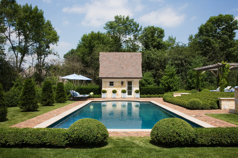 Ejemplo de casa de la piscina y piscina tradicional extra grande rectangular en patio trasero con adoquines de ladrillo