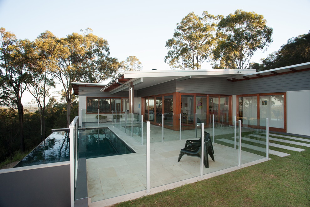 На фото: прямоугольный бассейн-инфинити среднего размера в современном стиле с покрытием из каменной брусчатки