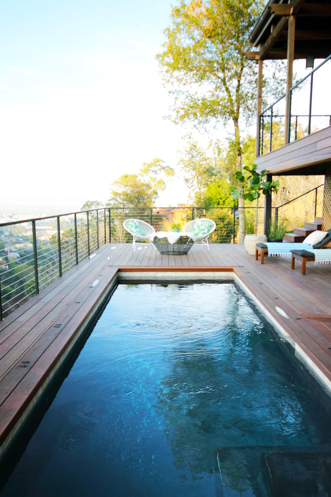 Cette image montre une piscine bohème de taille moyenne et rectangle avec une terrasse en bois.