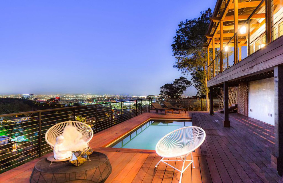 Cette photo montre une piscine éclectique de taille moyenne et rectangle avec une terrasse en bois.