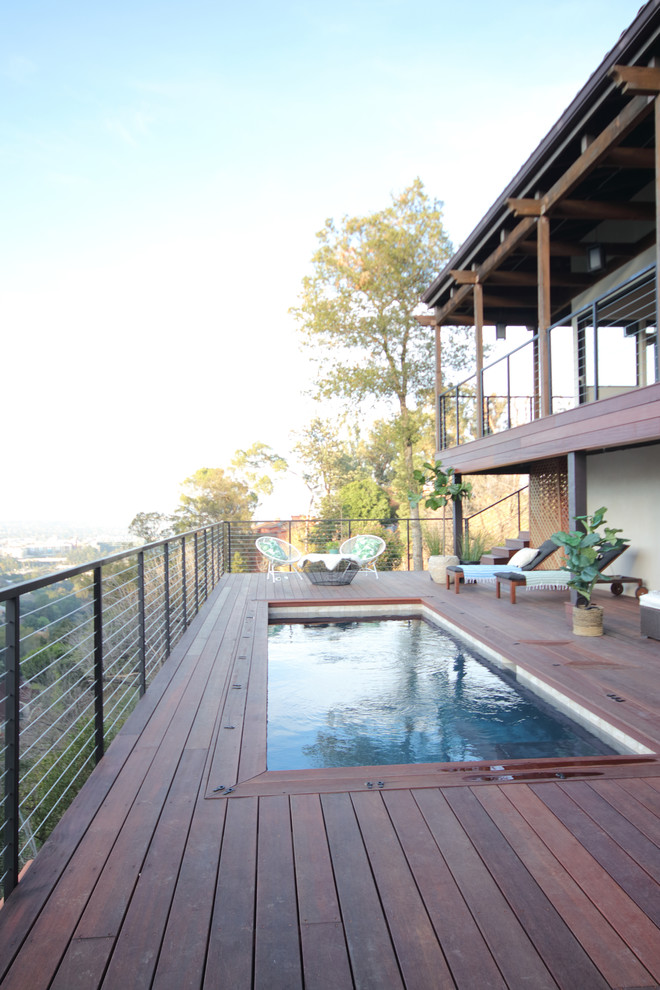 Diseño de piscina alargada rural de tamaño medio rectangular en patio trasero con entablado