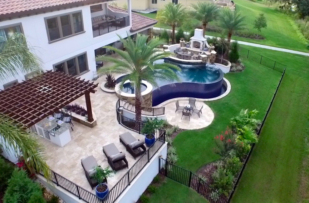 Immagine di una grande piscina a sfioro infinito tradizionale personalizzata dietro casa con fontane e pavimentazioni in pietra naturale