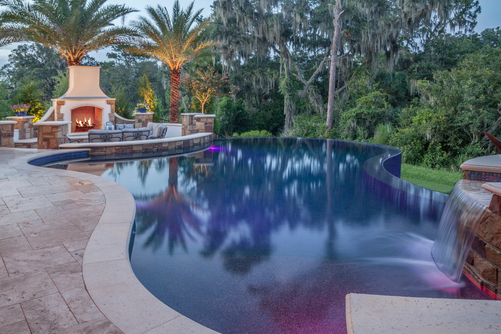 Ejemplo de piscina con fuente infinita clásica renovada grande a medida en patio trasero con adoquines de piedra natural