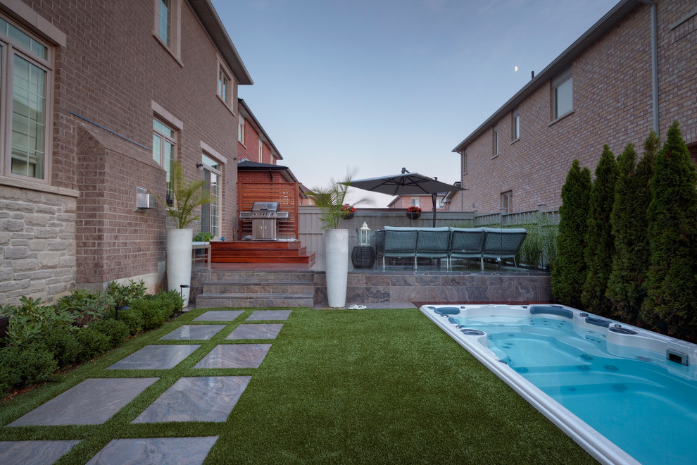 Foto di una piccola piscina monocorsia minimal rettangolare dietro casa con una vasca idromassaggio e pavimentazioni in pietra naturale