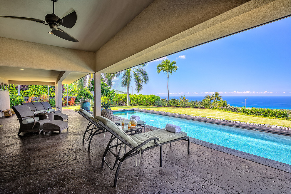Foto de piscina alargada tropical grande rectangular en patio trasero con losas de hormigón