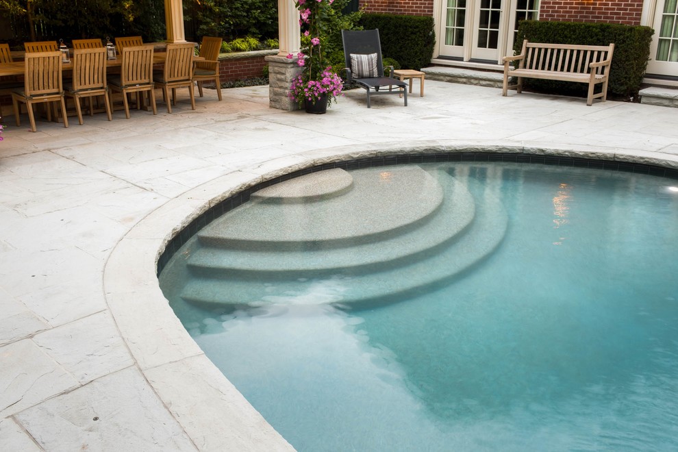 Inredning av en klassisk mellanstor njurformad pool på baksidan av huset, med naturstensplattor