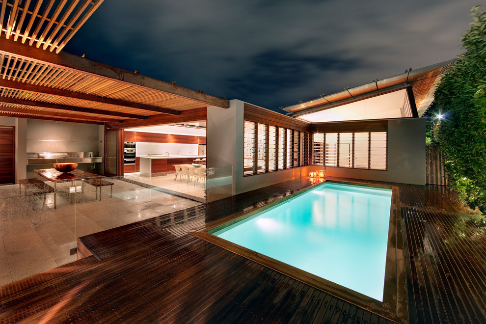 Inspiration pour une piscine design de taille moyenne et rectangle avec une terrasse en bois.