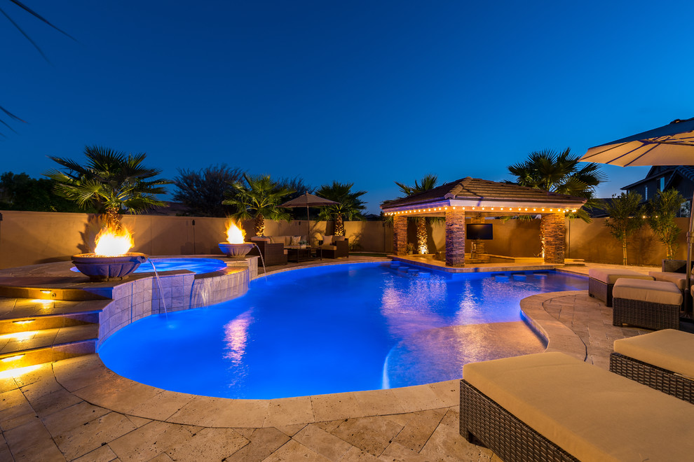 Photo of a large contemporary back custom shaped hot tub in Phoenix with natural stone paving.