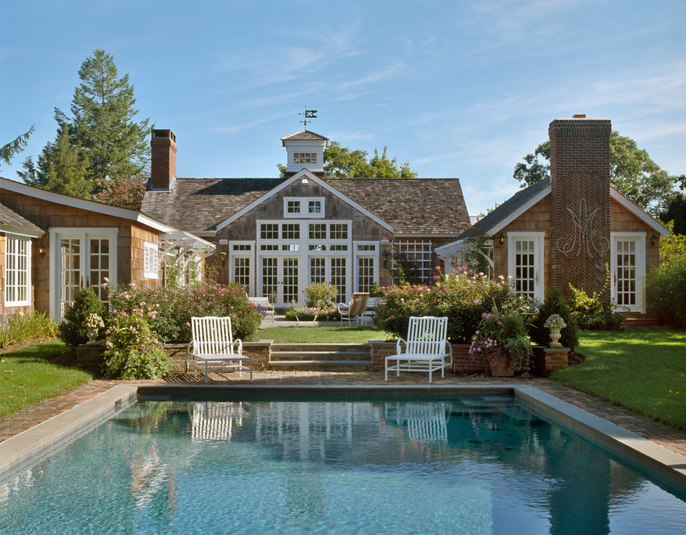 Photo of a large rural back rectangular natural swimming pool in New York with brick paving.