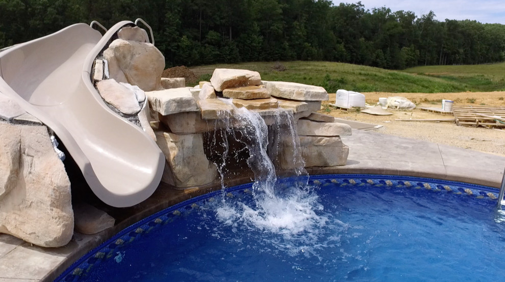На фото: большой естественный бассейн произвольной формы на боковом дворе в стиле ретро с водной горкой и покрытием из бетонных плит