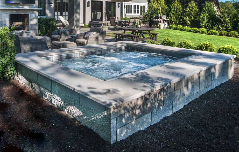 Ispirazione per una piccola piscina naturale tradizionale rettangolare dietro casa con una vasca idromassaggio e pavimentazioni in pietra naturale