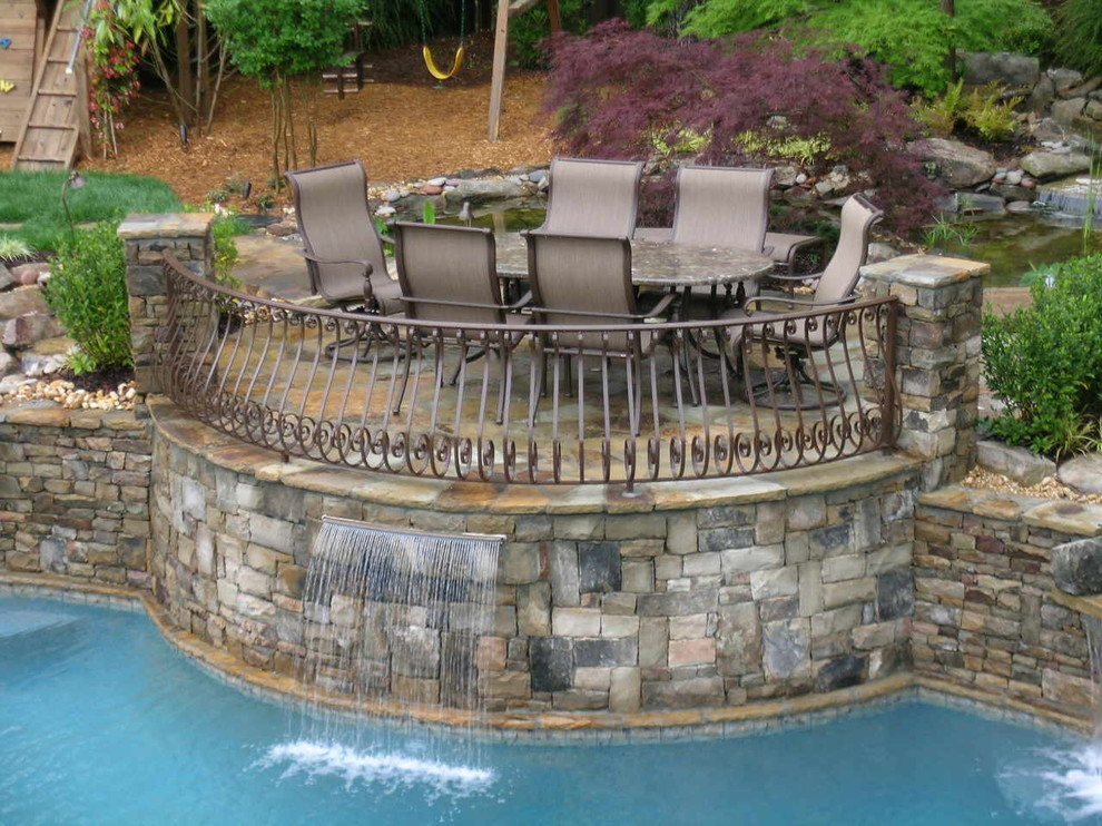 Modelo de piscina con fuente natural clásica grande a medida en patio trasero con adoquines de piedra natural