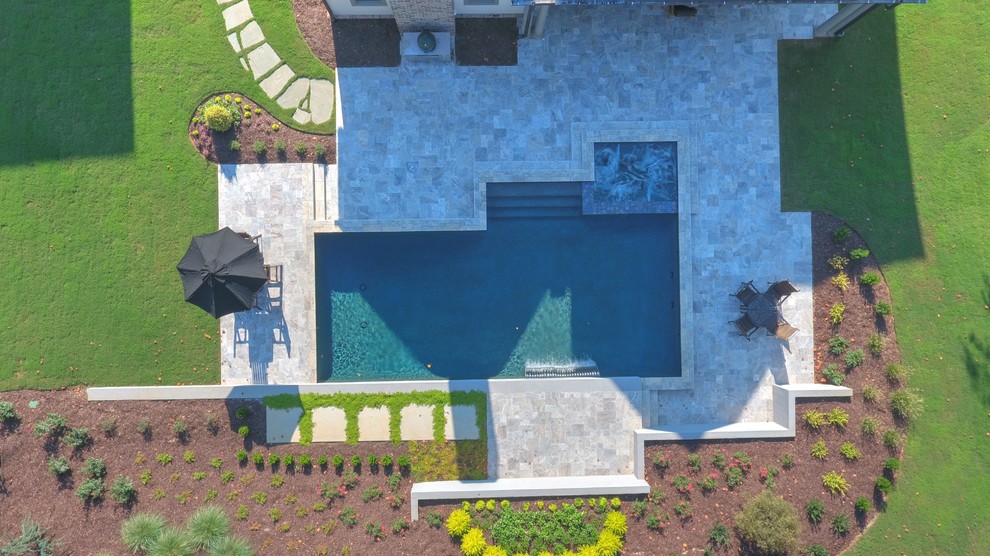 Immagine di una piscina classica personalizzata di medie dimensioni e dietro casa con pavimentazioni in pietra naturale e fontane