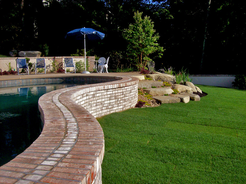 Modelo de piscinas y jacuzzis alargados rústicos grandes a medida en patio trasero con adoquines de piedra natural