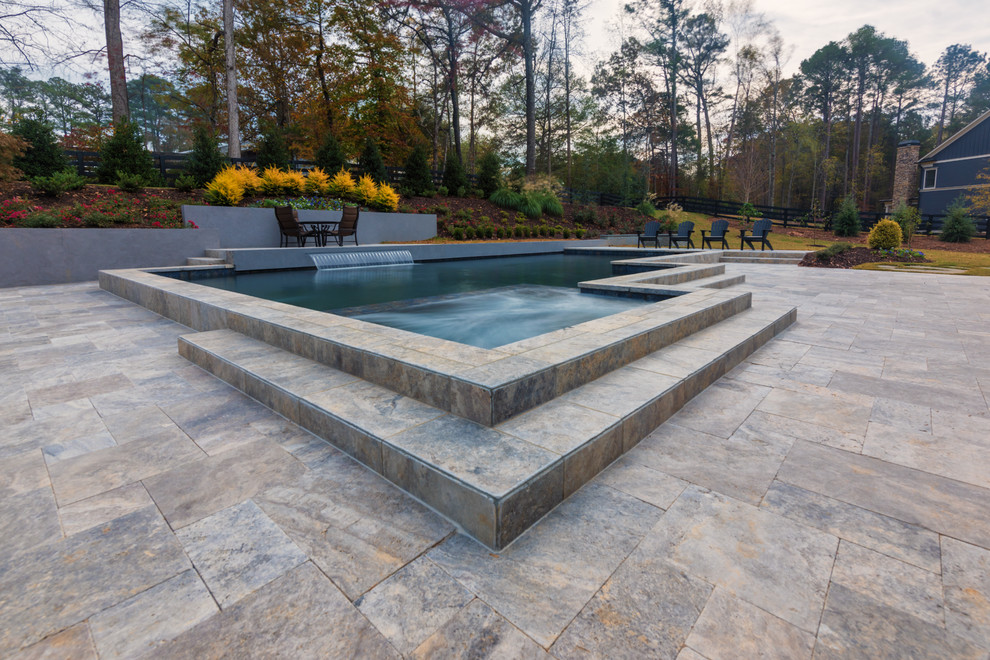 Immagine di una piscina contemporanea personalizzata di medie dimensioni e dietro casa con pavimentazioni in pietra naturale e fontane