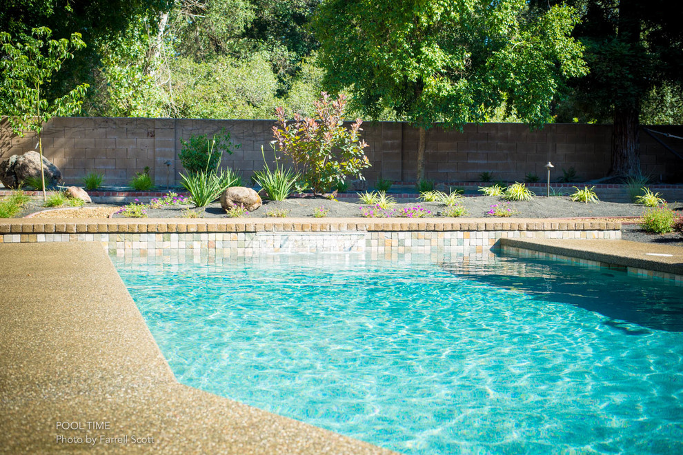 Cette image montre une piscine arrière traditionnelle de taille moyenne et rectangle avec un point d'eau et des pavés en brique.