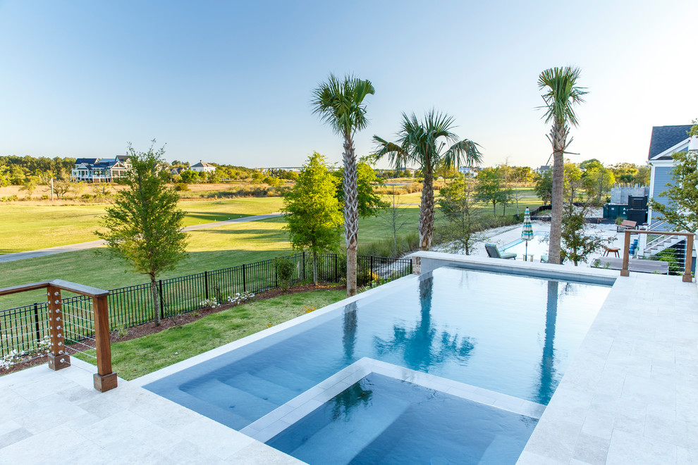 Foto di una piscina a sfioro infinito minimal rettangolare di medie dimensioni e dietro casa con una vasca idromassaggio e pavimentazioni in pietra naturale
