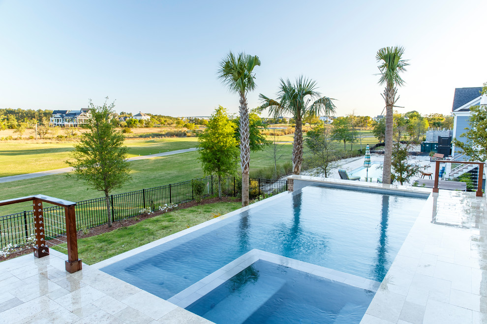 Cette image montre une piscine à débordement et arrière design de taille moyenne et rectangle avec un bain bouillonnant et des pavés en pierre naturelle.