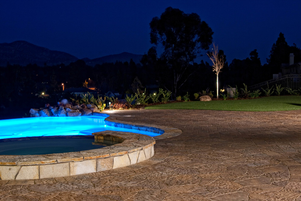 Foto de piscinas y jacuzzis naturales clásicos renovados grandes a medida en patio trasero con adoquines de hormigón