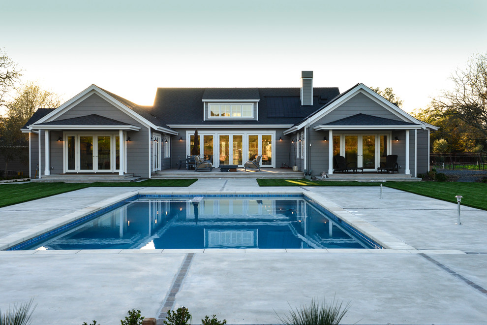 Immagine di una grande piscina monocorsia country rettangolare dietro casa con lastre di cemento