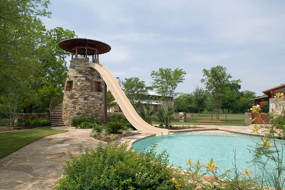 Réalisation d'une piscine naturelle et arrière champêtre de taille moyenne et sur mesure avec un toboggan et des pavés en pierre naturelle.