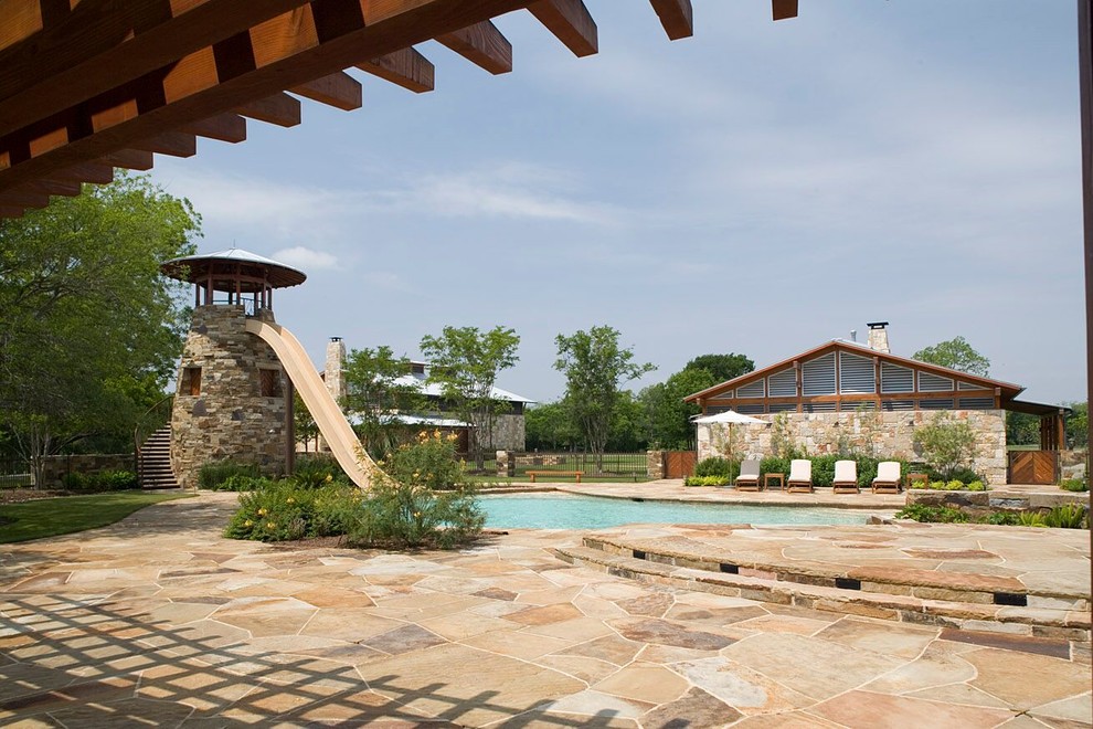 Réalisation d'une piscine naturelle et arrière champêtre de taille moyenne et sur mesure avec un toboggan et des pavés en pierre naturelle.