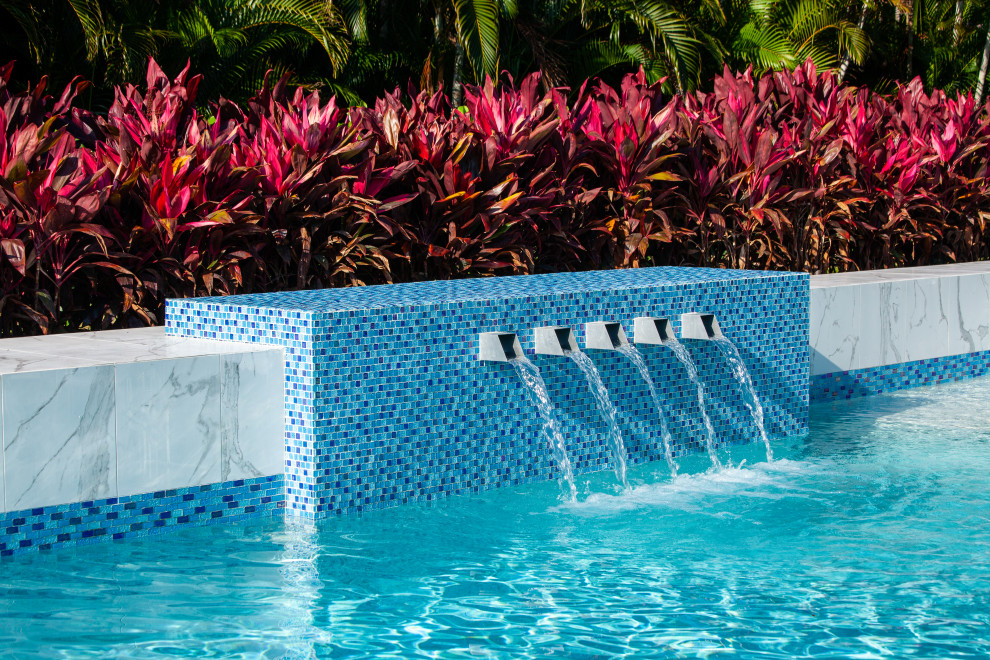 Cette image montre une grande piscine arrière minimaliste sur mesure avec un point d'eau et des pavés en pierre naturelle.