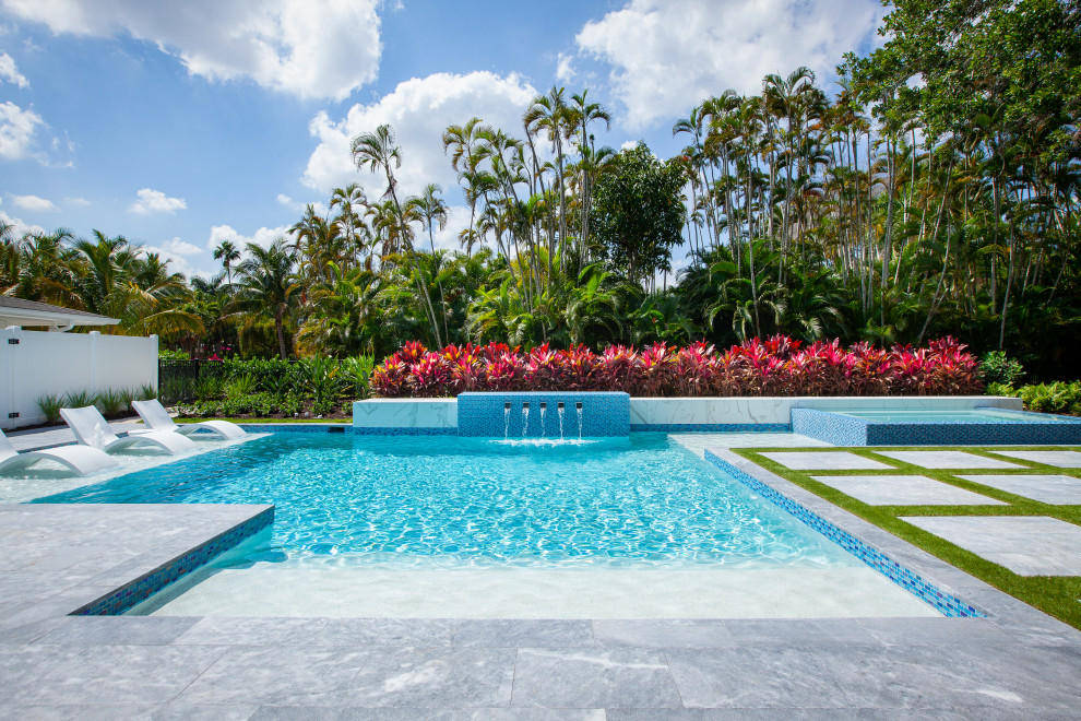 Großes Mid-Century Sportbecken hinter dem Haus in individueller Form mit Wasserspiel und Natursteinplatten in Miami