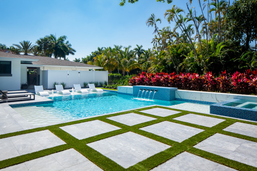 Imagen de piscina con fuente alargada minimalista grande a medida en patio trasero con adoquines de piedra natural