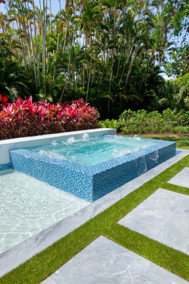 Diseño de piscina con fuente minimalista grande a medida en patio trasero con adoquines de piedra natural