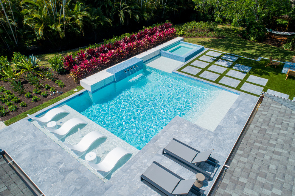 Imagen de piscina con fuente moderna grande a medida en patio trasero con adoquines de piedra natural
