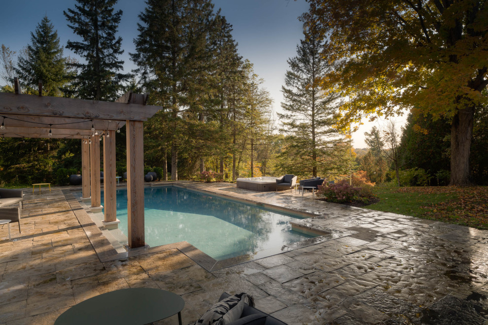 Foto på en stor lantlig pool på baksidan av huset, med spabad och naturstensplattor