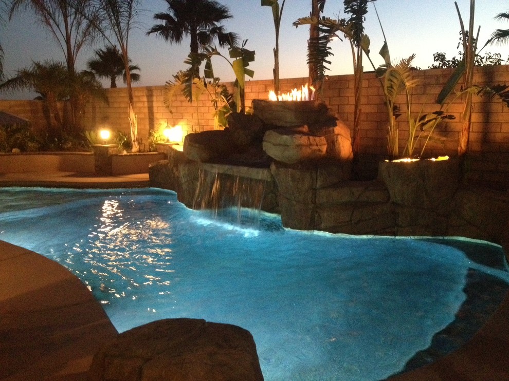 Foto di una piscina naturale tropicale personalizzata di medie dimensioni e dietro casa con fontane e cemento stampato