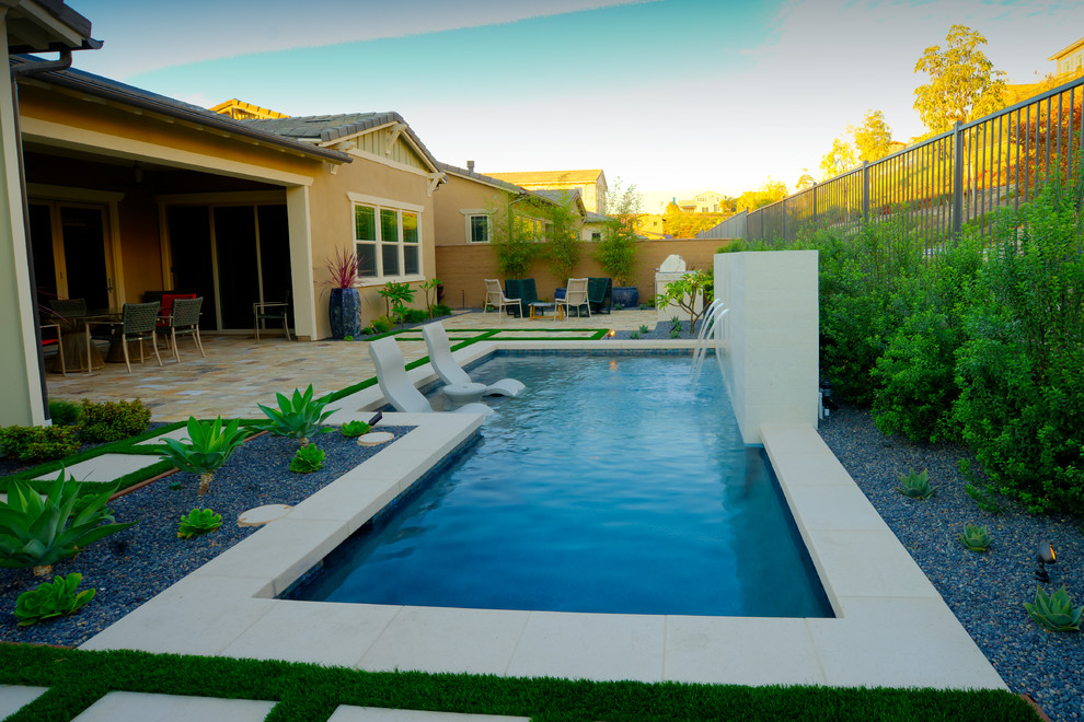 Exemple d'une petite piscine arrière tendance rectangle avec un bain bouillonnant et des pavés en pierre naturelle.